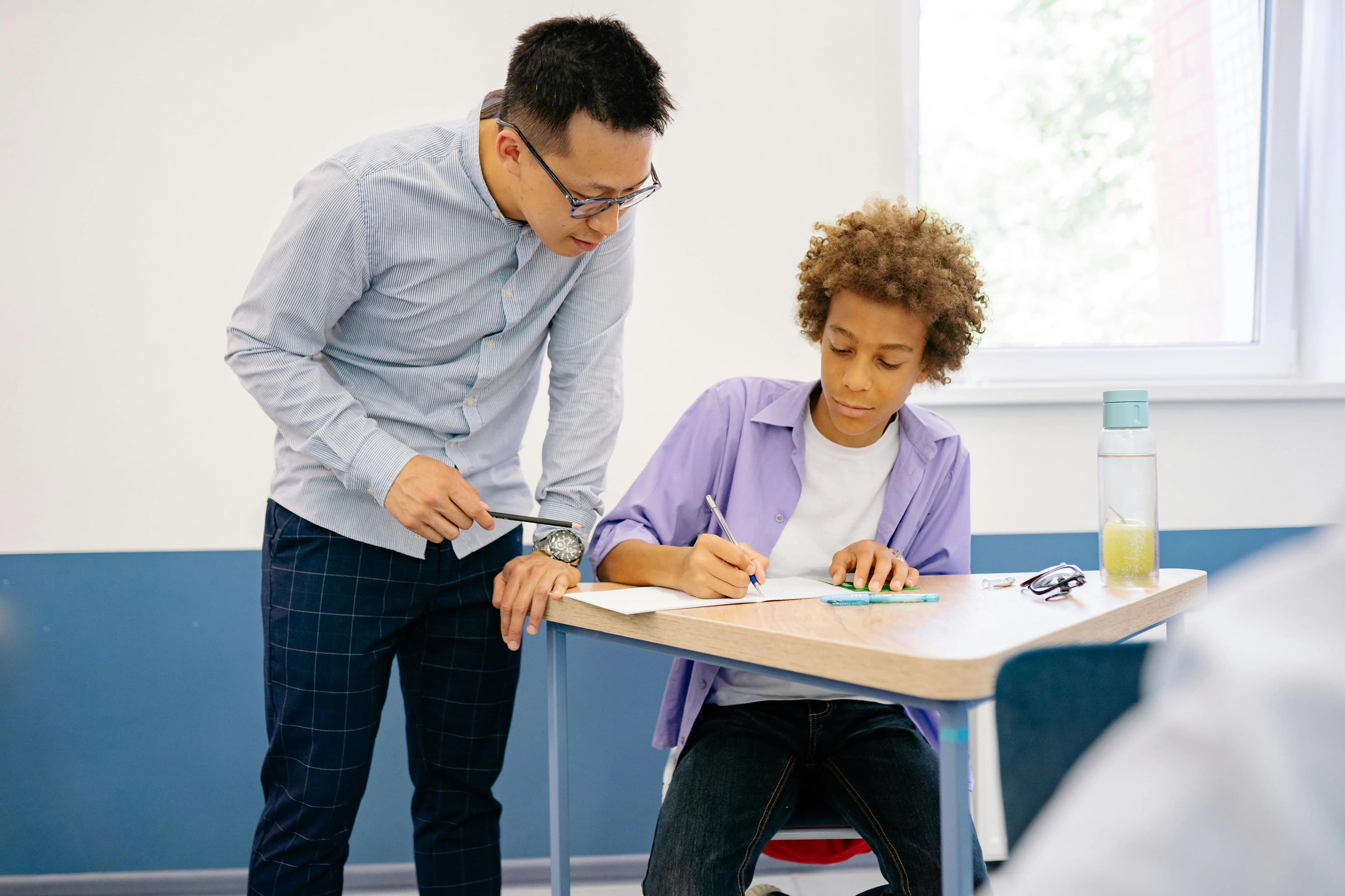 Teacher guiding a secondary-school student through a written exercise